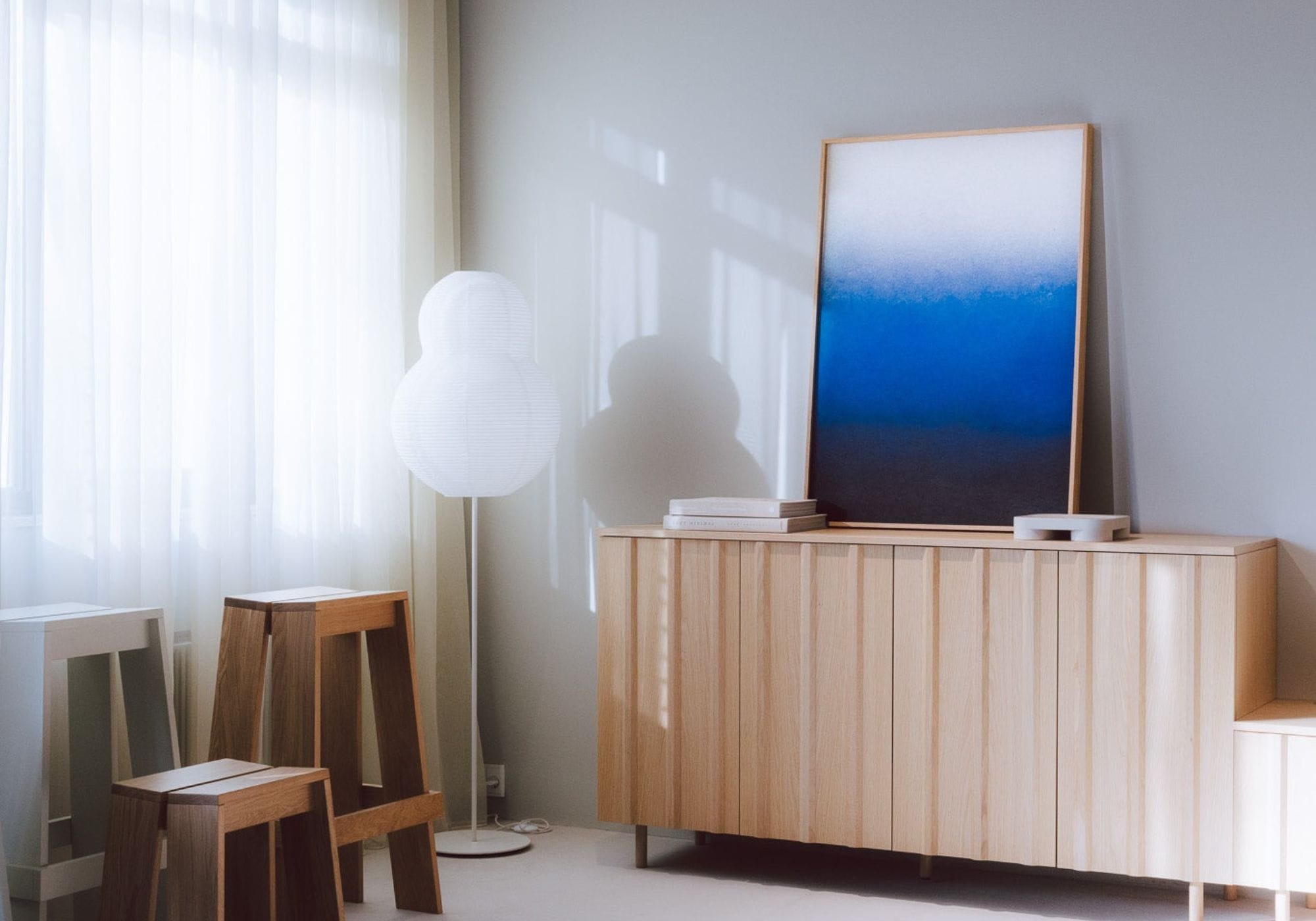 Decorative soundproofing panel with a calming blue gradient, placed on a wooden sideboard in a bright and modern interior.
