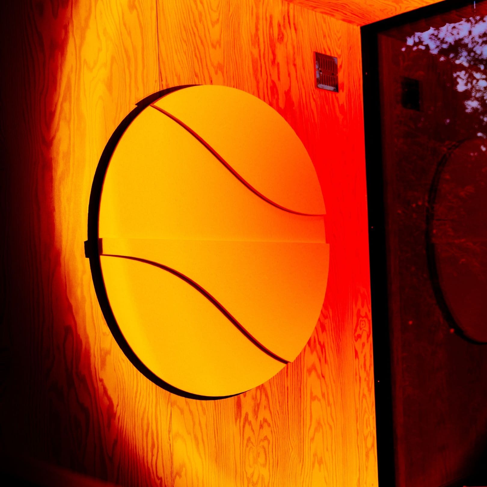 Round acoustic artwork with curved lines, illuminated with warm red and orange lighting.